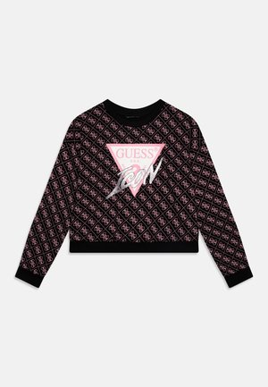 Pull court noir avec un motif géométrique rose et blanc. Comprend un grand logo triangle rose avec "GUESS U.S.A." et des accents argentés.