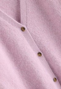 Lyserød uldcardigan med en blød tekstur, der har V-hals, brune knapper og en let fnugget finish.