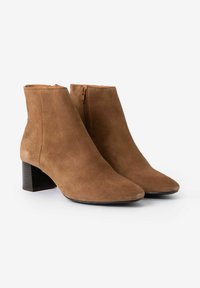 Braune Wildleder-Stiefeletten mit spitzer Spitze, seitlichem Reißverschluss und mittelhohem Blockabsatz. Glatte Textur mit mattem Finish.