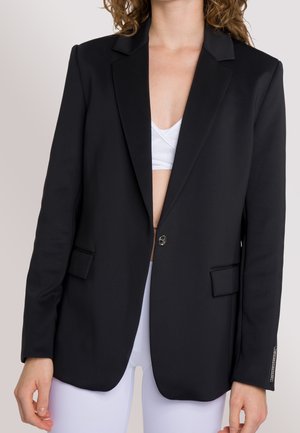 Blazer nero con spalle strutturate, chiusura a un bottone e due tasche frontali. Tessuto liscio e vestibilità su misura, adatto per abbigliamento formale.
