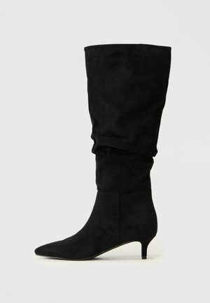 Cizme din suede negre, până la genunchi, cu un design lejer; vârf ascuțit și toc joș, cu o formă compactă. Textură netedă, fără elemente metalice vizibile sau modele.