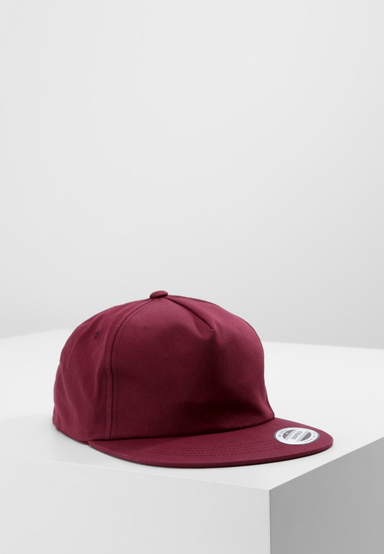 Burgundy színű baseball sapka lapos karimával, sima anyagból készült; a tetején egy gomb, az oldalon pedig egy címke található.
