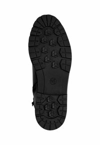 Semelle de botte noire avec un caoutchouc texturé et robuste, présentant des motifs de semelle hexagonaux pour une meilleure adhérence, et un bord lisse autour du périmètre.