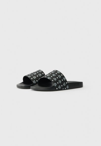 Black slip-on sandals with textured soles and wide straps featuring white MCM logo and diamond patterns.
