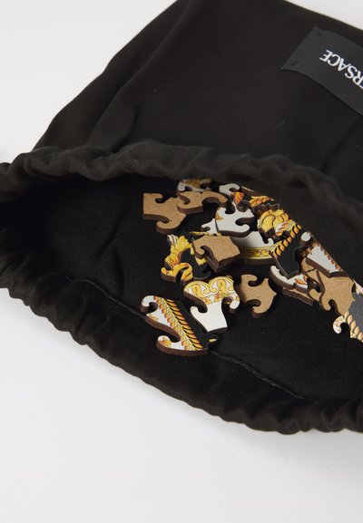 Black fabric pouch with elastic top, containing colorful puzzle pieces featuring intricate designs in various shapes and textures.