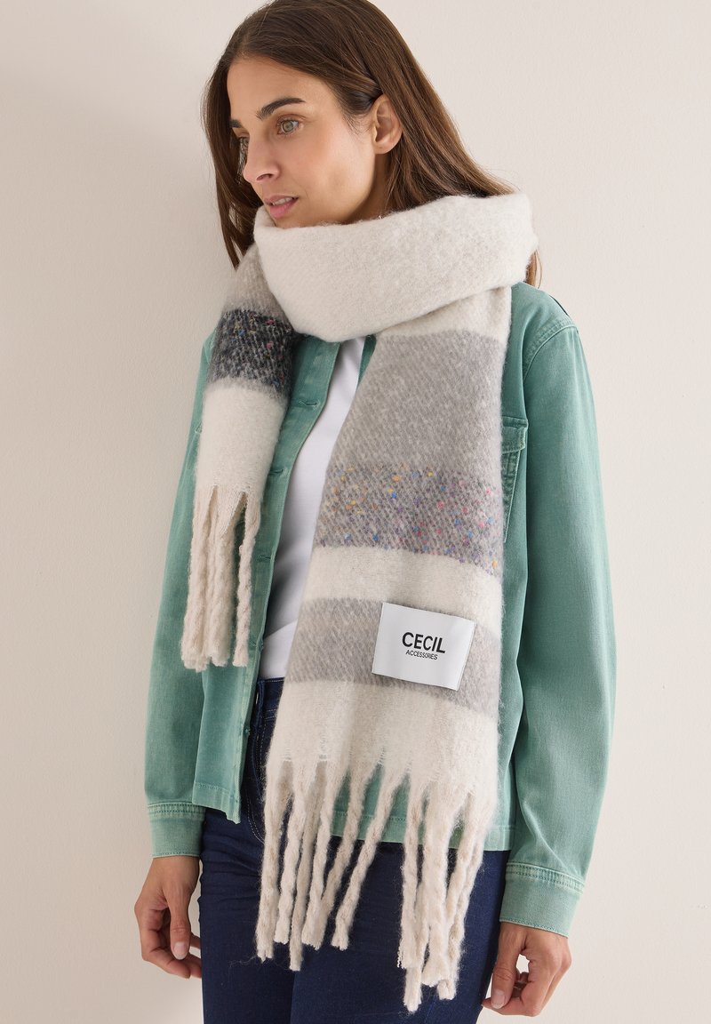 Wollmischungsschal mit grauen und cremefarbenen Streifen, Fransenrändern und einem auffälligen Etikett mit "Cecil Accessories" auf einer weichen, strukturierten Oberfläche.