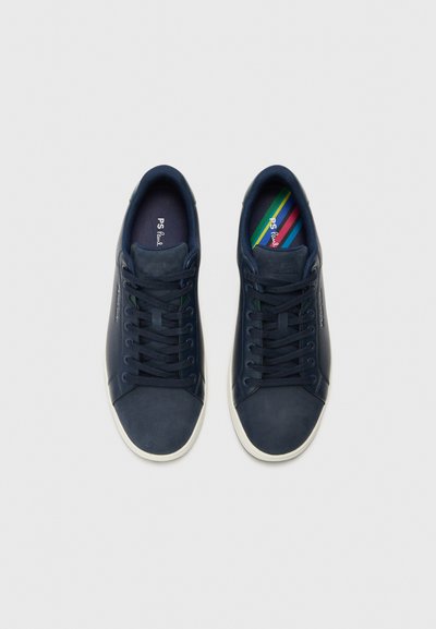 Marinblå lädersneakers med rundad tå, platta snören och vita gummisulor. Innersulorna har ett randigt mönster i grönt, blått och rött.