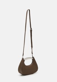 Brązowa torebka z sztucznej skóry o zaokrąglonym kształcie, z metalowymi elementami w kolorze srebrnym i regulowanym paskiem. Posiada okrągłe wycięcie na górze.