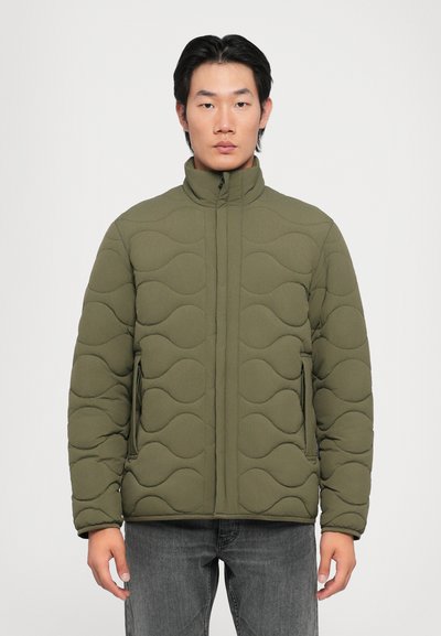 Veste rembourrée olive vert avec un motif de couture ondulé, col montant et fermeture éclair, dotée de deux poches latérales et d'une finition texturée.
