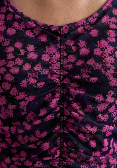 Haut imprimé floral en violet et noir avec un design froncé. Présente un col rond et un tissu texturé.