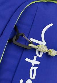 Blaues Stofftasche mit leuchtend grünen Akzenten, ausgestattet mit einem schwarzen Karabinerclip und einem strukturierten Seil mit einem Knoten, das ein weißes Logo-Detail zeigt.