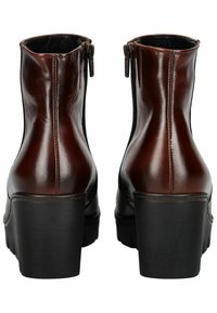 Bottines en cuir marron avec une finition lisse, des fermetures éclair sur le côté et des talons épais noirs. Détails en couture le long des coutures.