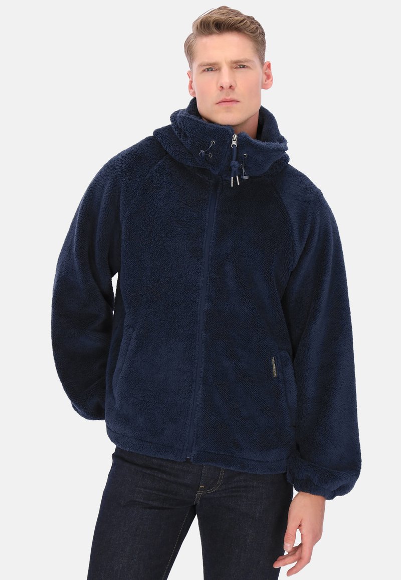 Granatowa kurtka polarowa z wysokim kołnierzem, zapięciem na zamek i elastycznymi mankietami. Teksturowana, miękka tkanina, luźny krój oraz boczne kieszenie.