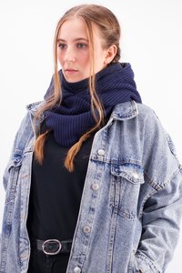 Chunky, navy knit infinity scarf with a textured pattern, layered over a black top, paired with a denim jacket featuring silver buttons.