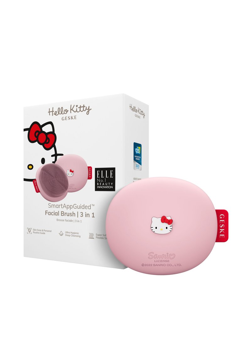 Spazzola per il viso Hello Kitty di colore rosa, con una forma liscia e arrotondata e dettagli del personaggio in rilievo; include una scatola bianca con nome del marchio e informazioni del prodotto.