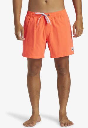 Bright orange swim shorts with a drawstring closure, elastic waistband, and a small logo patch on the left leg. Smooth fabric texture.
