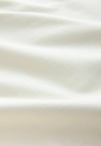 Kremna tkanina z gladko teksturo, ki ima nežne diagonalne vzorce tkanja in mehke gube, kar nakazuje na mehkobo in padanje.