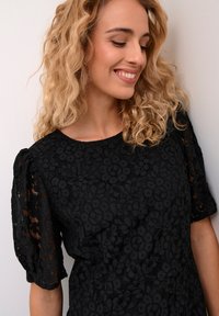 Black lace top with short puffed sleeves, featuring a floral pattern and textured finish. Round neckline complements elegant design.