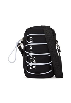 Črna torbica čez ramo z belimi elastičnimi vrvicami, srebrno opremo in napisom "KARL LAGERFELD JEANS" v belem spredaj, opremljena s širokim črnim trakom.