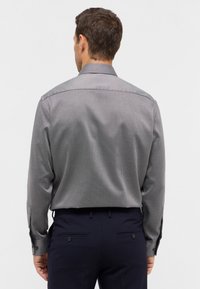 Grau gemustertes Langarmhemd mit strukturiertem Kragen, Knopfmanschetten und glatter Textur, kombiniert mit dunkelblauen Hosen.