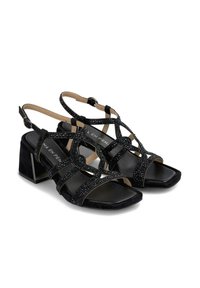 Sandali neri con tacco a spillo, realizzati in suede, con cinturini decorativi adornati da strass e punta quadrata. Tacco a blocco grosso.