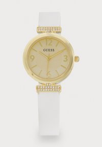 Montre analogique dorée avec un bracelet en silicone blanc. Caractéristiques d'un cadran doré texturé, d'accents clairs sur la lunette et d'embellissements en cristal.