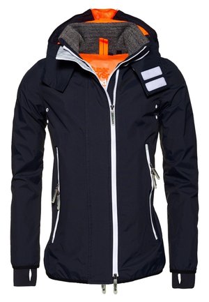 Marineblaue Kapuzenjacke mit leuchtend oranger Fütterung, durchgehendem weißen Reißverschluss, seitlichen Reißverschlusstaschen und Daumenlöchern an den Ärmeln.