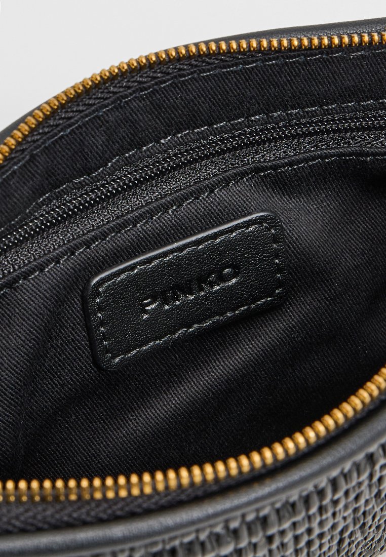 Wnętrze czarnej saszetki na zamek z tkaninowym wykończeniem, wewnętrzną kieszonką na zamek oraz skórzaną metką.
