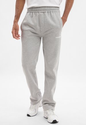 Grijze sweatpants met een elastische tailleband, zijzakken en een klein wit logo. Zachte textuur, rechte pijpen.