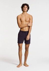 Ciemnofioletowe spodenki kąpielowe z elastycznym paskiem w talii i sznurkiem do regulacji. Zaprojektowane w prostym, eleganckim stylu z lekkiego materiału.