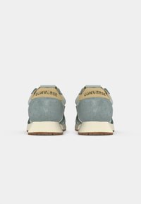 Two rear-facing sneakers featuring a light blue upper with textured suede and tan accents, branded with "CONVERSE" at the heel, on a white background.