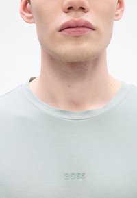Light gray short-sleeve t-shirt made of smooth fabric, featuring a subtle embossed "BOSS" logo on the chest and a crew neckline.