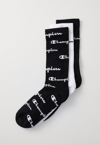 Calcetines acanalados en blanco y negro con el logo de "Champion" en blanco. El diseño incluye un patrón de texto repetitivo. Estilo atlético clásico.