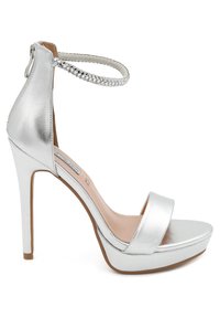 Sandali con tacco alto argentati con una finitura metallica lucida, caratterizzati da una ampia fascia frontale, una cinghia alla caviglia con dettagli intrecciati e una suola piattaformata.