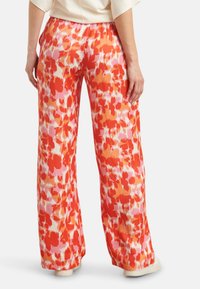 Floral-print wide-leg pants featuring shades of red and pink, with an elastic waistband and smooth, lightweight fabric.