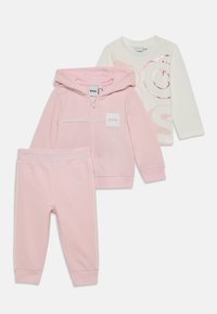 Conjunto infantil de três peças: uma sweatshirt rosa com fecho, calças de moletom rosas e uma camisola de manga longa branca com um logótipo rosa. Tecido suave e casual.