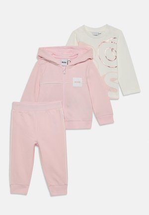 Three-piece children's outfit: a pink zip-up hoodie, pink sweatpants, and a white long-sleeve shirt with a pink logo. Soft, casual fabric.