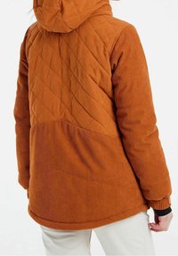 Braune Cordjacke mit einem gesteppten, diamantförmigen Rücken, Kapuze und gerippten Bündchen; bietet eine lockere Passform und eine weiche Textur.