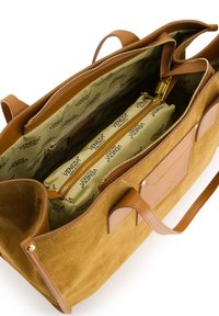 Torebka tote w kolorze suede w odcieniu tan z brązowymi skórzanymi akcentami. Posiada przestronną wnękę, kieszeń na zamek oraz wyłożona jest markowym materiałem.