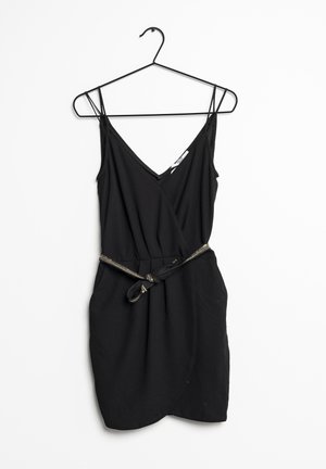 Schwarzes ärmelloses Kleid mit V-Ausschnitt, Wickeldesign und einem passenden Stoffgürtel mit metallischem Akzent. Glatte Textur. Hänkt an einem schwarzen Haken.