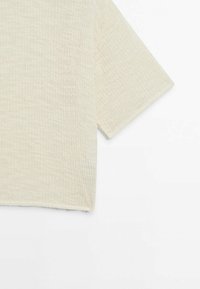 Lys beige, kortærmet top lavet af struktureret stof; har en afslappet form og en enkel, udekoreret design.