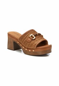 Sandalo estivo in pelle intrecciata marrone con tacco platform, dettagli dorati e borchie lungo la suola. Punta aperta con fibbia decorativa.
