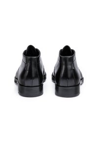 Schwarze Leder-Ankle-Boots mit glatter Oberfläche, runden Zehen und flachen Absätzen. Sie weisen minimale Nähte auf und besitzen ein dezentes Logo-Tag an der Seite.