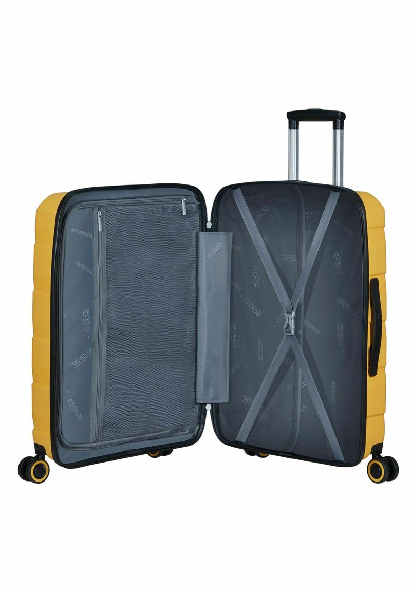 Gele harde koffer met een gestructureerd oppervlak, dubbele ritscompartimenten en een grijze binnenkant. Beschikt over vier wielen en een uitschuifbare handgreep.