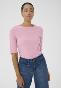 Roze geribbelde top met een scalloped halslijn en korte mouwen, gecombineerd met high-waisted blauwe denim jeans met achterzakken.