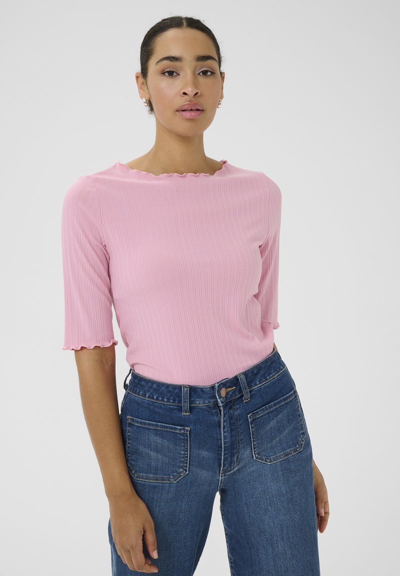 Roze geribbelde top met een scalloped halslijn en korte mouwen, gecombineerd met high-waisted blauwe denim jeans met achterzakken.