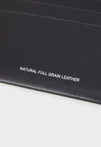 Black natural full grain leather with a smooth texture, featuring the embossed text "NATURAL FULL GRAIN LEATHER" in white.