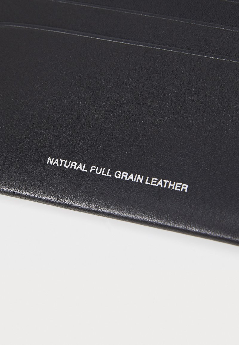 Svart naturligt fullkorns läder med en slät yta, med den präglade texten "NATURLIGT FULLKORNS LÄDER" i vitt.