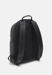 Sac à dos noir avec une surface texturée, panneau dorsal en maille rembourré, straps réglables et une poignée supérieure. Fermeture éclair avec quincaillerie de marque.