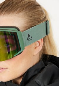 Lunettes de ski vertes avec des verres miroités, dotées d'une sangle texturée et d'un détail de logo. La monture a un design rectangulaire, améliorant la visibilité.